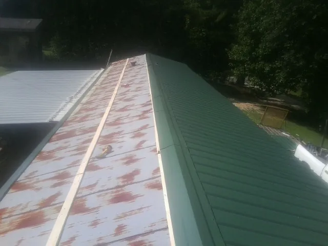 Old rusted panels beside newly installed green metal roofing — Wind Damage Roof Repair by Roofing Brothers in Pitsburg