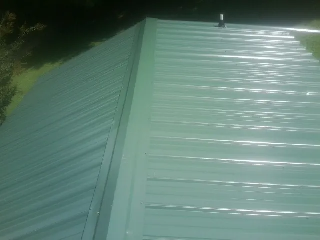 New green metal panels meeting at the ridge of a roof — Flat Roof Repair work by our crew in Pitsburg