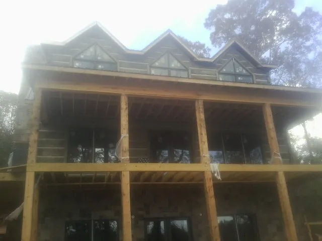 Dormers and porch framing on a large log home under construction — Roof Coating work by our crew in Pitsburg