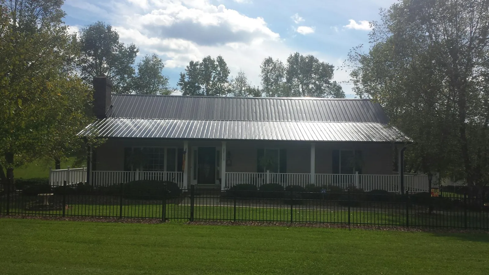 Gray metal roof on a brick ranch with a full width front porch — Gutter Guard Installation work by our crew in Pitsburg