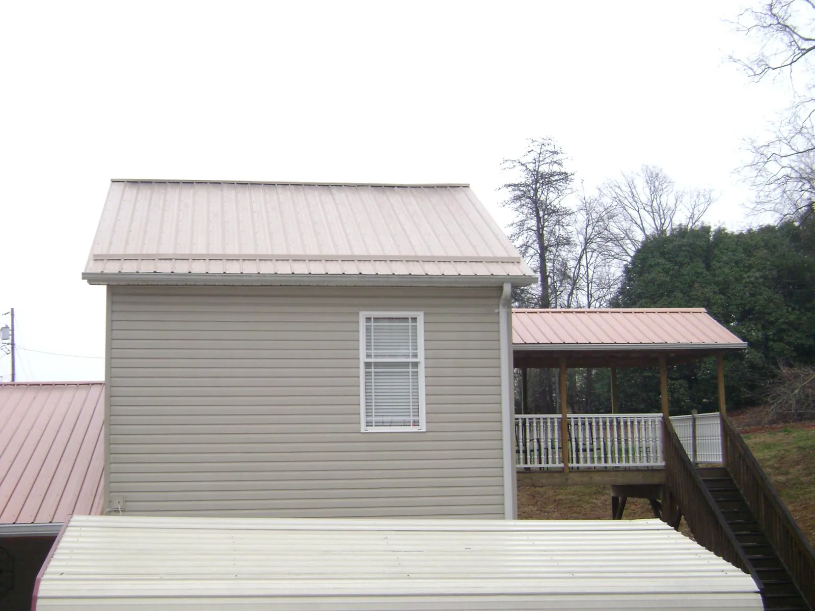 Tan metal roofs on a two story addition and attached porch, from a Roof Replacement job in Pitsburg
