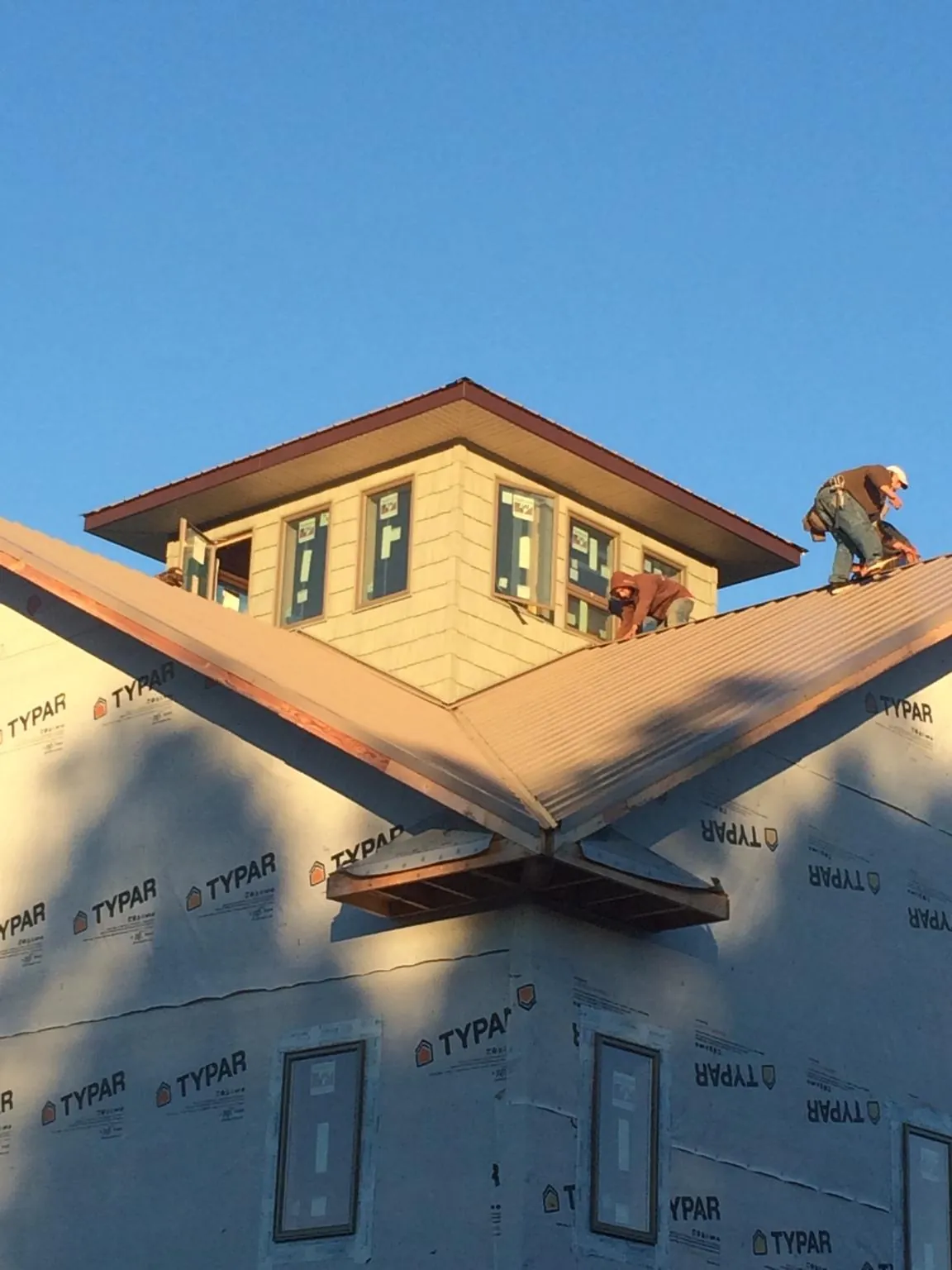 Roofers working around a rooftop cupola on a new metal roof at sunset — Roof Waterproofing in Pitsburg by Roofing Brothers